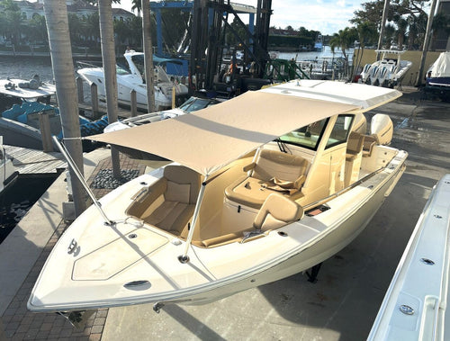 Beige Scout center console boat with a custom tan National Canvas sun shade at the dock
