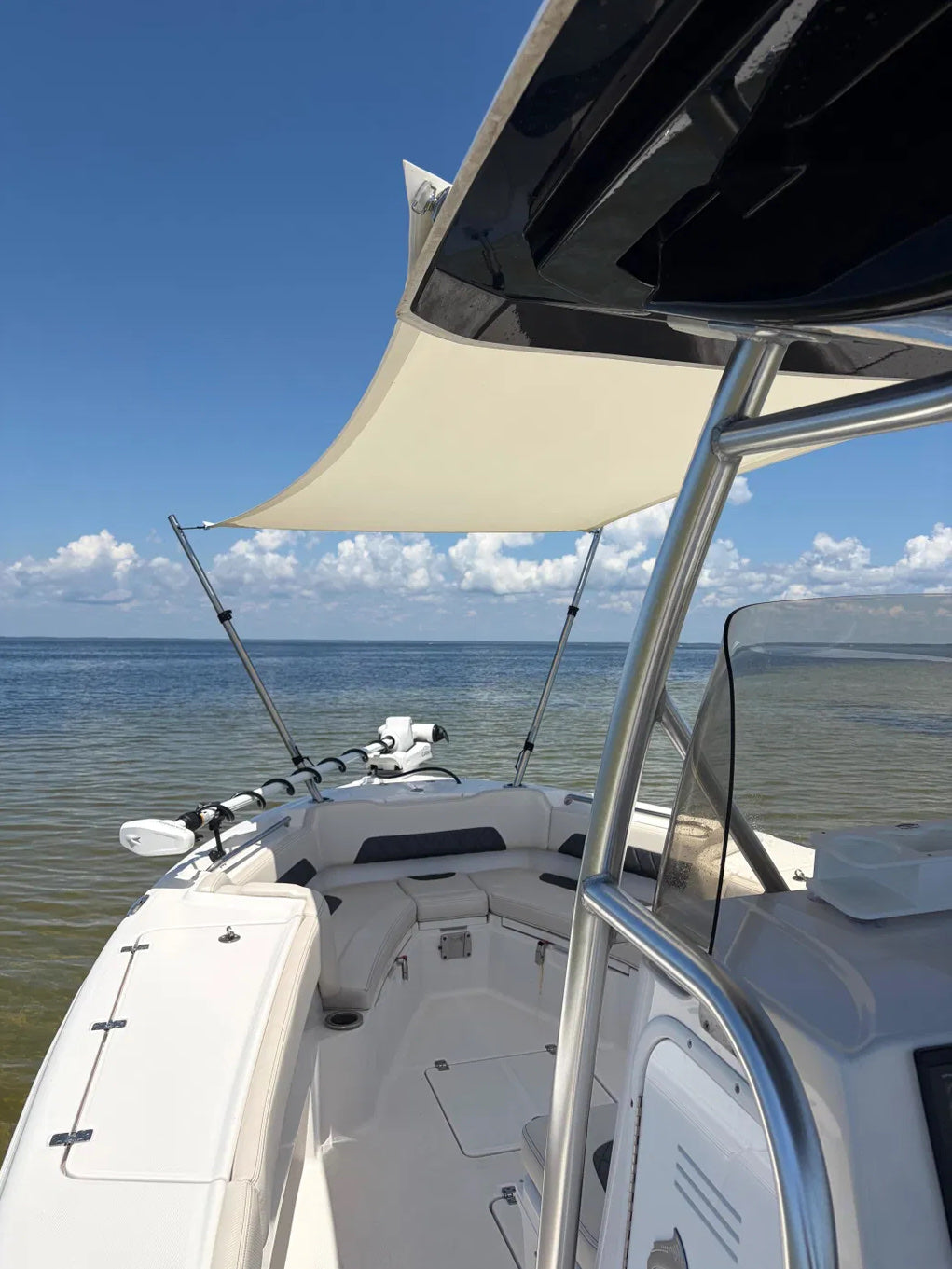 View from the helm of a cream custom bow Sunshade shading the bow seating of a center console on open water